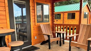 A wooden cabin with a porch, two tables, and four chairs. - Lakehouse Resort Bugtussle Sierra 2 Near Rend Lake (Benton)