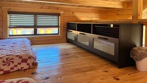 A wooden cabin room with a bed, a window with blinds, a kitchenette, and a trash bin. - Lakehouse Resort Bugtussle Sierra 2 Near Rend Lake (Benton)