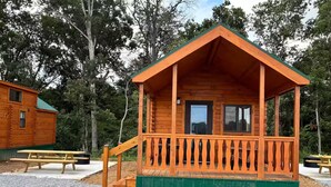 A wooden cabin with a porch, a window, and a door. - Lakehouse Resort Bugtussle Sierra 2 Near Rend Lake (Benton)
