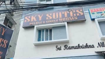 Un edificio con un letrero que dice 'SKY SUITES DELUXE & SINGLE ROOM' y otro letrero que anuncia 'KAKATHI TEA, TIFNNS, N'.