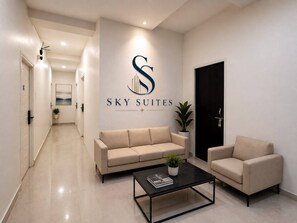 Hotellin aula, jossa on sohva, nojatuoli ja sohvapöytä. Kyltissä lukee »SKY SUITES».