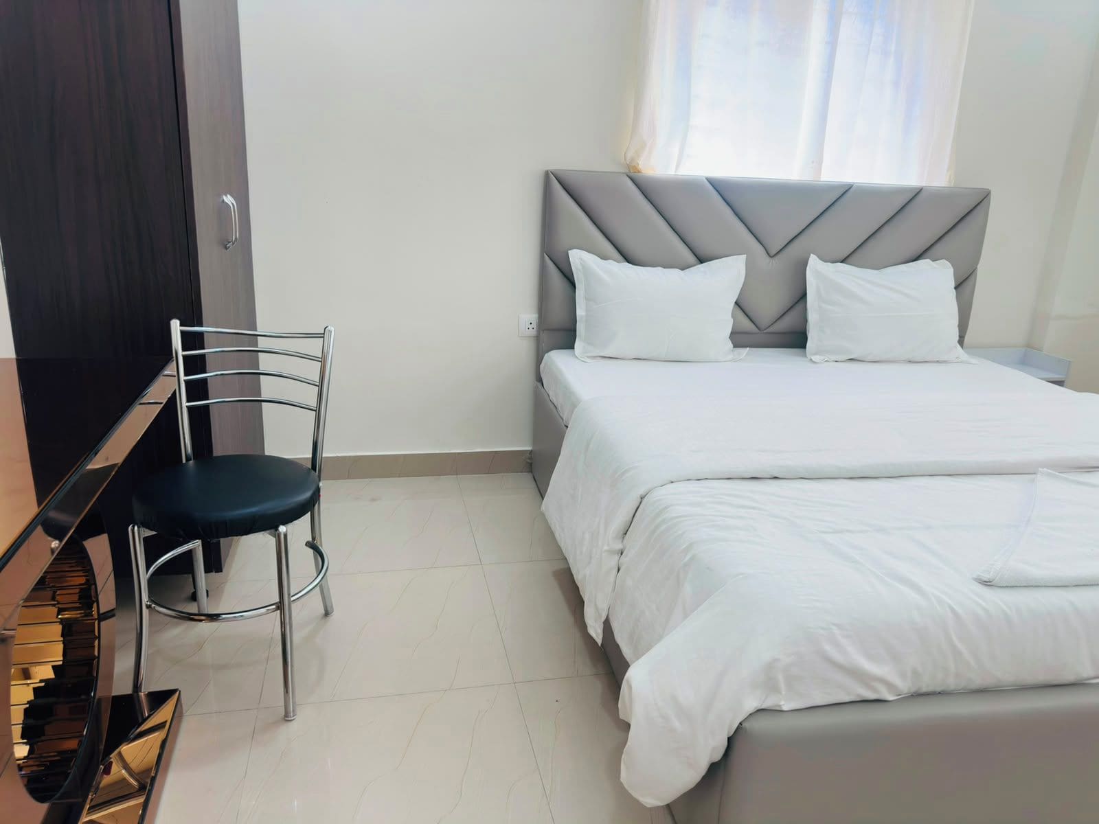 Una habitación de hotel con una cama, una silla y un armario.