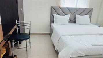 Una habitación de hotel con una cama, una silla y un armario.