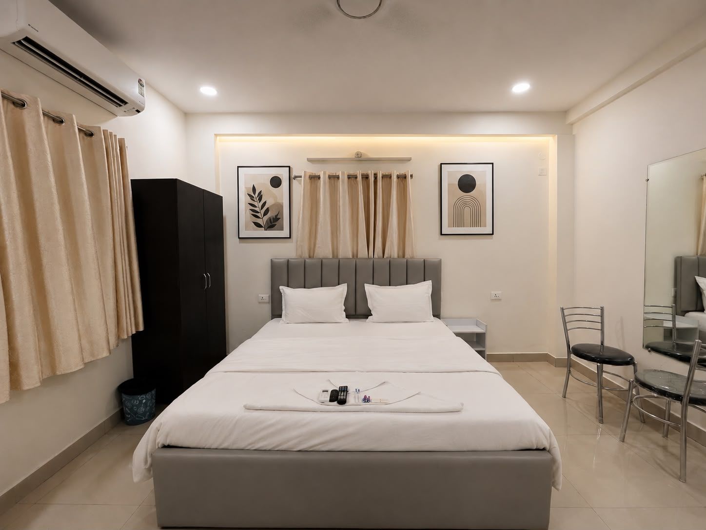 A hotel room with a bed, a wardrobe, a desk, a chair, and a mirror.