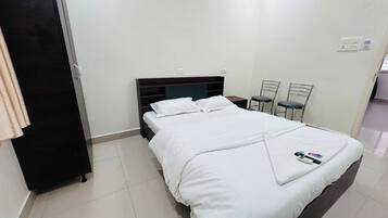 Una habitación de hotel con una cama, un escritorio, dos sillas y un armario.