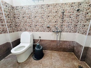 Een badkamer met toilet, een hygiëneschuimer en een douche.