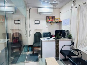 Een kantoor met een bureau, computer, stoelen en een glazen scheidingswand.