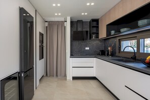 Eine moderne Küche mit integrierten Geräten, einem großen Fenster und Blick ins Freie.