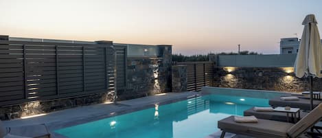 A rooftop swimming pool with lounge chairs and a stone wall.