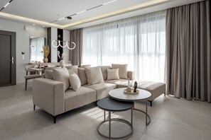 Ein modernes Wohnzimmer mit einer Eckcouch, einem runden Couchtisch und einem Essbereich im Hintergrund.