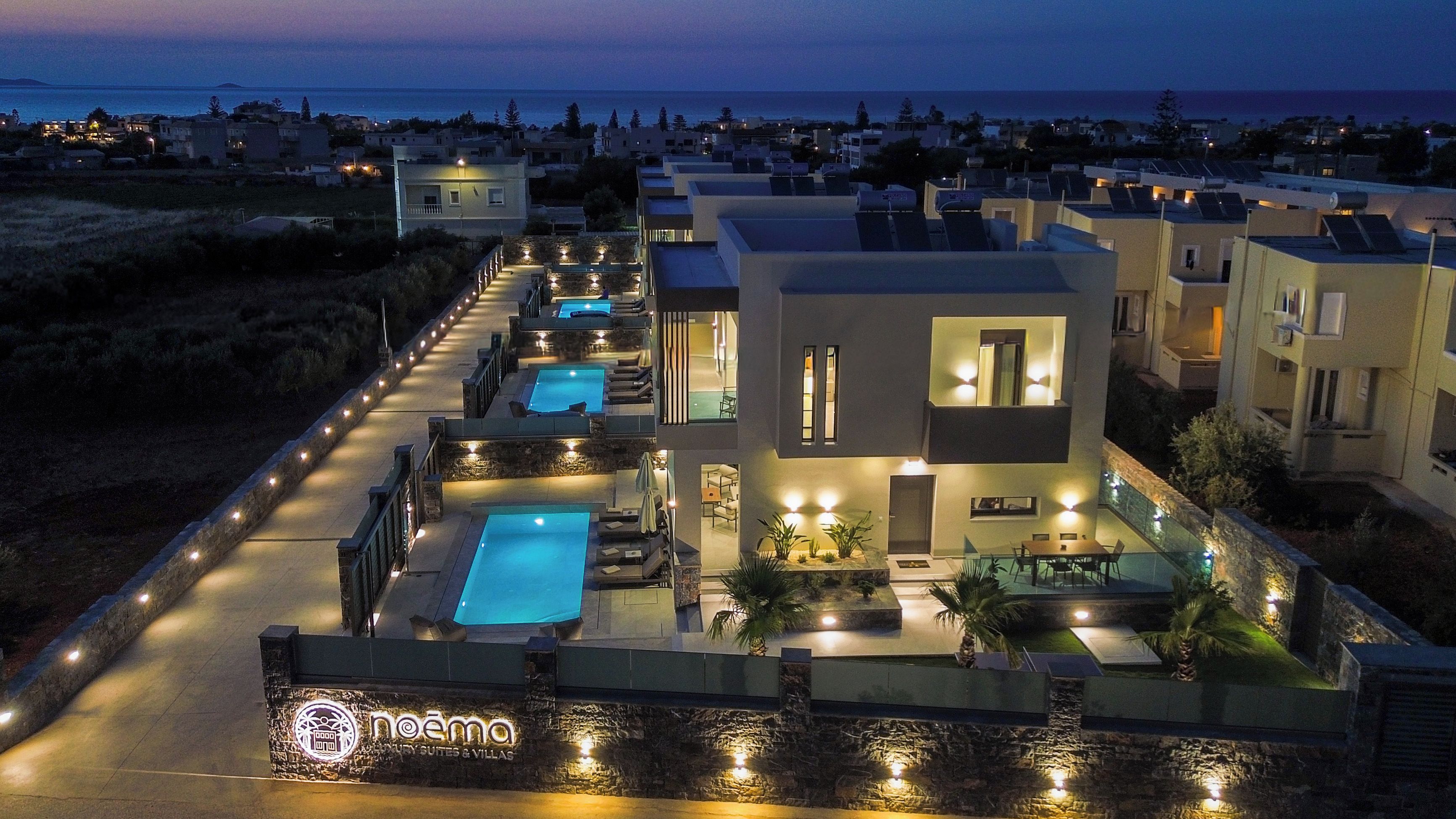 Ein modernes Resort mit mehreren Schwimmbecken, einem gut beleuchteten Weg und Blick aufs Meer.