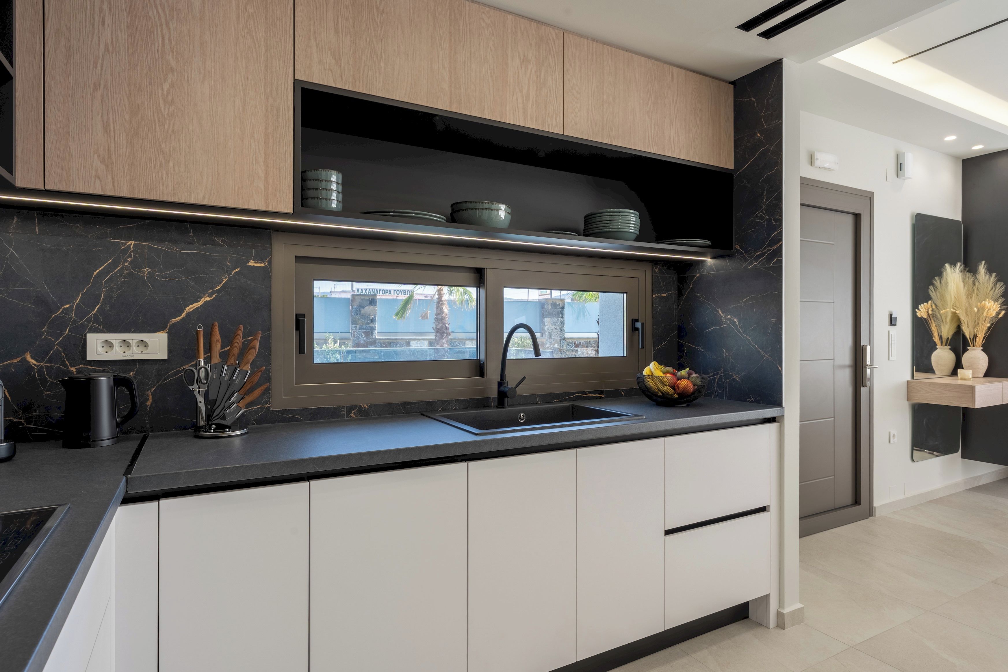 Eine moderne Küche mit schwarzem Arbeitsplatz, weißen Schränken und einem eingebauten Backofen.
