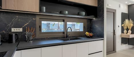 Una cocina moderna con encimera negra, armarios blancos y horno integrado.