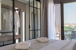 Ein Hotelzimmer mit Bett, Bademantel und Balkon mit Aussicht.