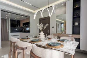 Ein moderner Essbereich mit einem Marmortisch, gewebten Platzsets und einer Blumenvase.