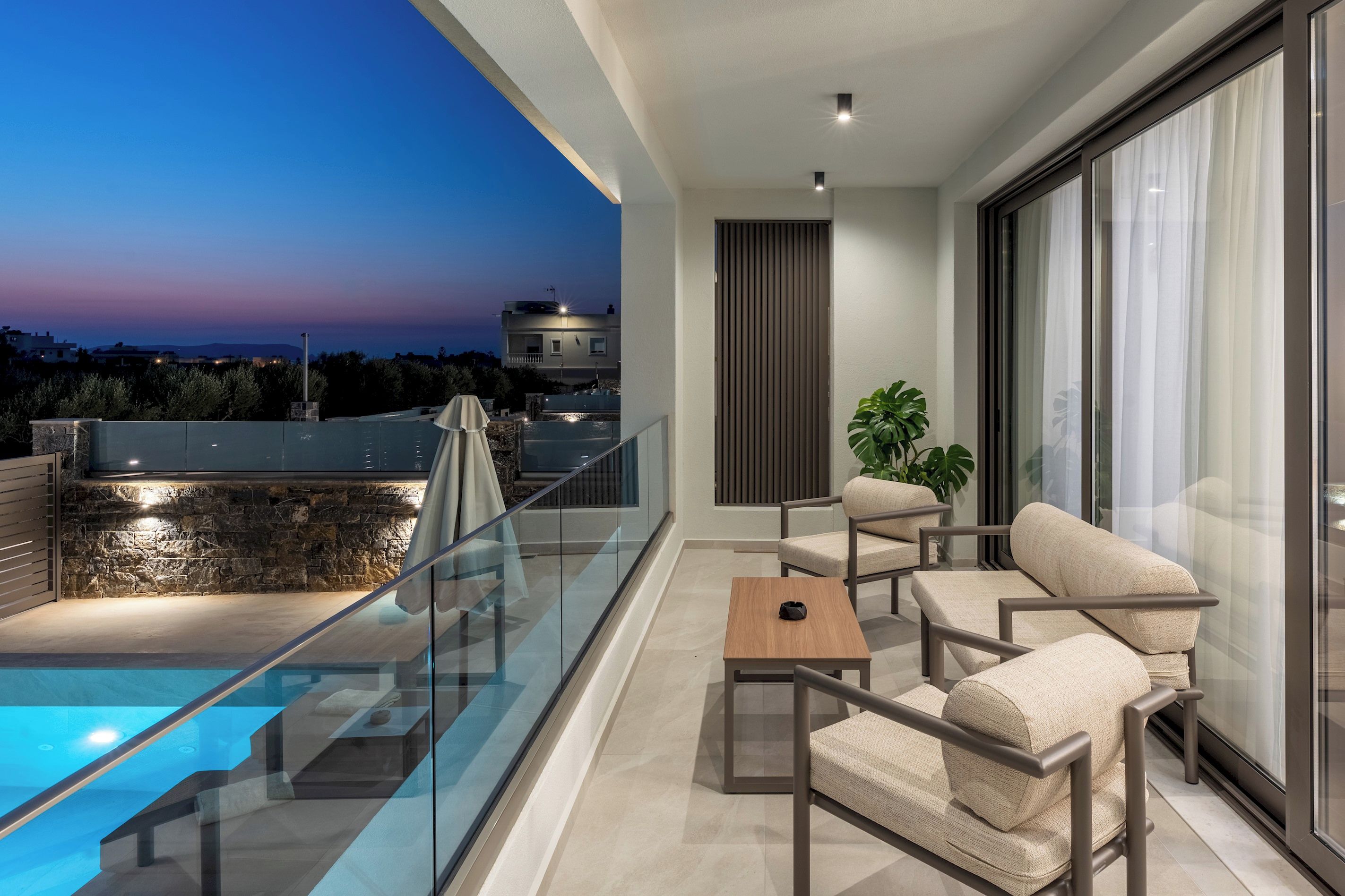 Ein Balkon mit Pool, Sitzgelegenheit und Blick auf die Stadt bei Dämmerung.