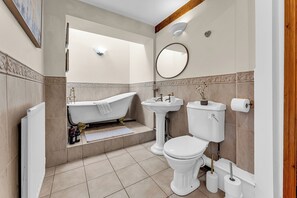 A bathroom with a bathtub, sink, toilet, and a mirror on the wall. - Oxhay Barn (Newcastle-Under-Lyme)