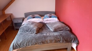A bed with a grey bedspread and two pillows, a nightstand with a drawer, and a wooden bench. - Country House "Gîte Des Hautes Falaises" with Shared Garden and Wi-Fi (Saint-Léonard)
