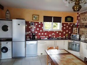 A compact kitchen with a washing machine, a coffee maker, a microwave, and a sink. - Country House "Gîte Des Hautes Falaises" with Shared Garden and Wi-Fi (Saint-Léonard)