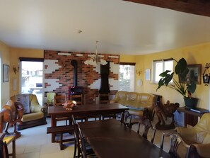 A dining area with a brick wall, wooden furniture, and a large plant. - Country House "Gîte Des Hautes Falaises" with Shared Garden and Wi-Fi (Saint-Léonard)