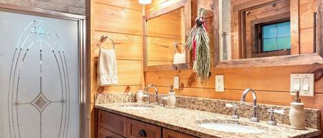 A wooden bathroom with two sinks, a mirror, and a towel rack.