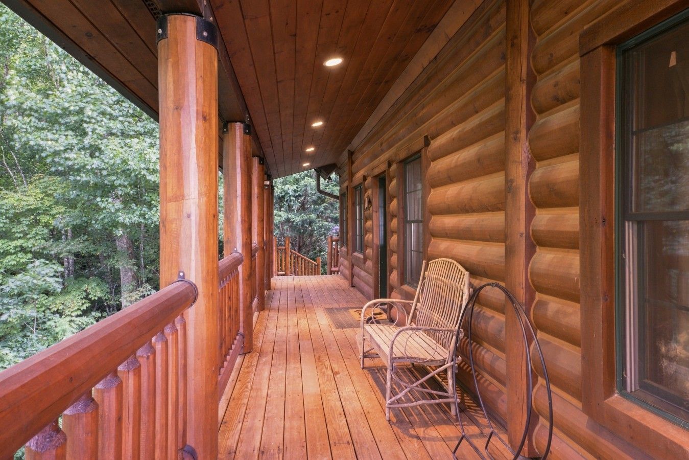 A wooden log cabin with a wooden deck and a chair.