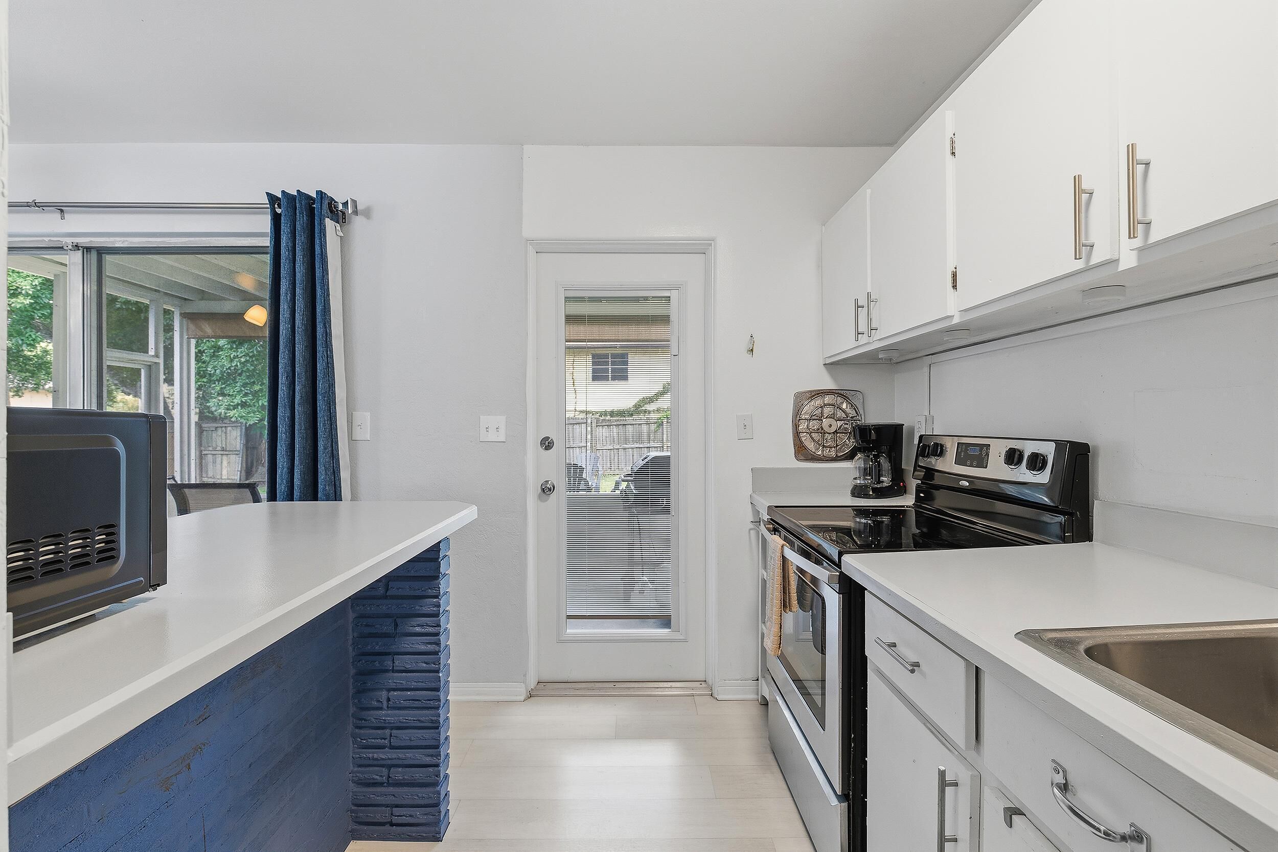 Une cuisine compacte avec des meubles blancs, un four encastré et une cuisinière.