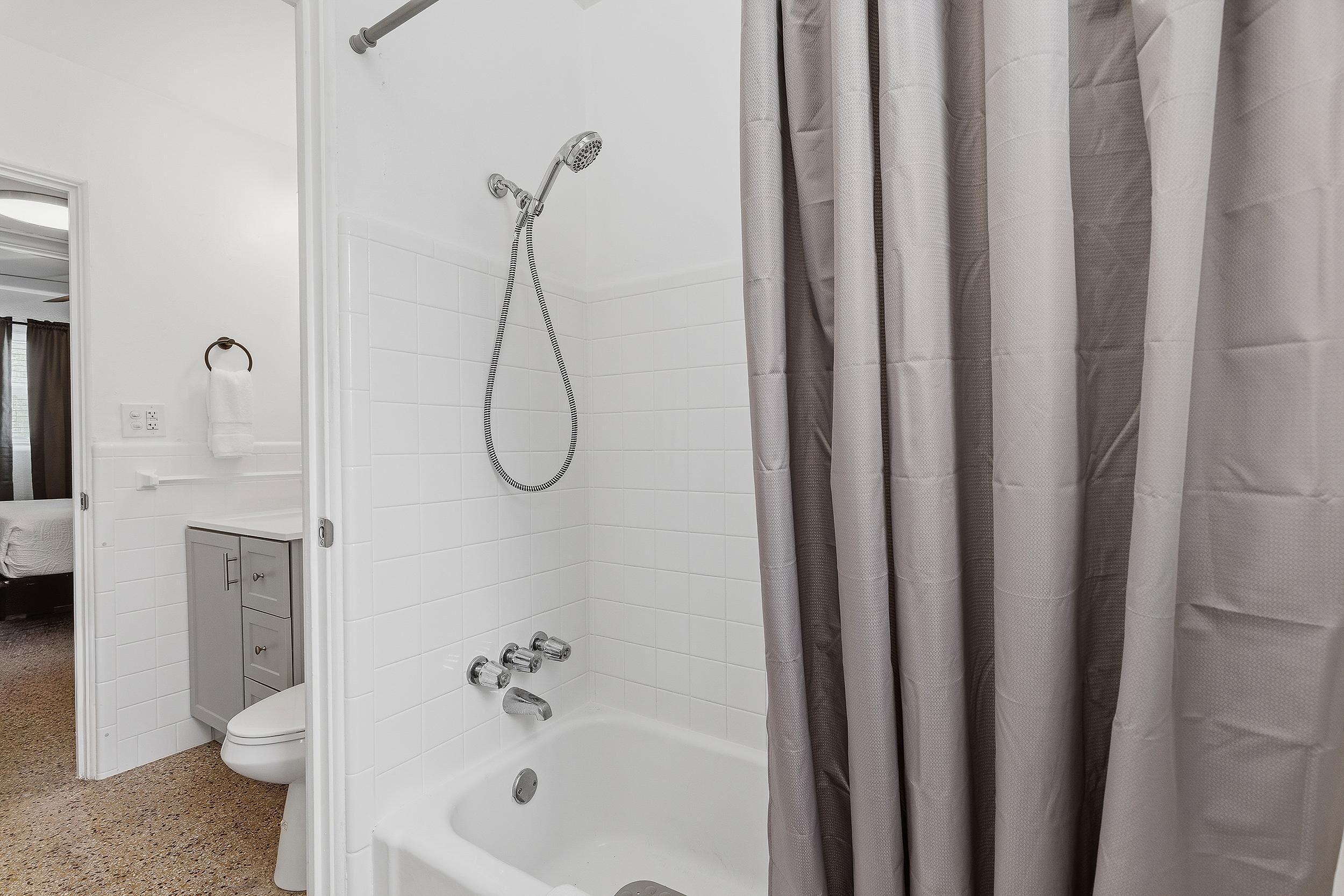 Et badeværelse med badekar, bruser og toilet.