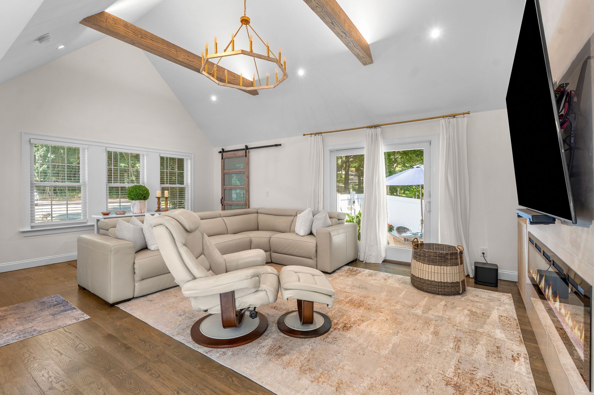 A spacious living room with a large L-shaped sectional sofa, a fireplace, and a television.