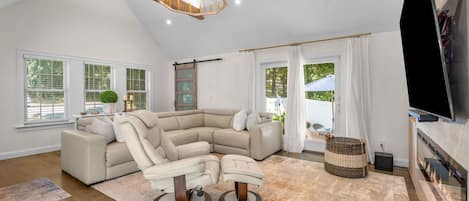 A spacious living room with a large L-shaped sectional sofa, a fireplace, and a television.