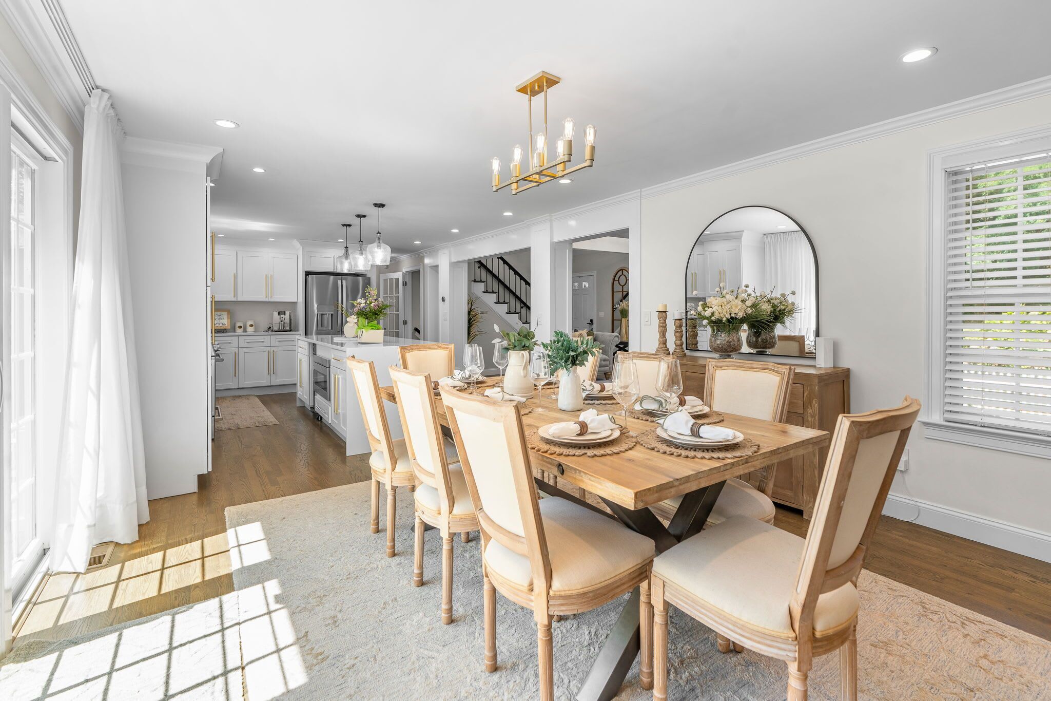 A modern kitchen with white cabinets, a stainless steel refrigerator, and a dining area with a wooden table and chairs.