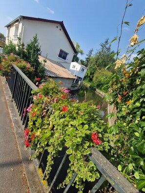 Un quartier résidentiel avec un bâtiment blanc, une clôture en métal et de la verdure.