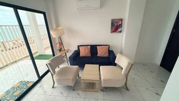 A modern living room with a blue sofa, two armchairs, a coffee table, and a floor lamp.