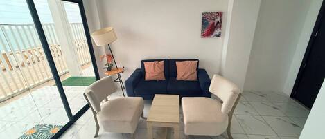 Una sala de estar moderna con un sofá azul, dos sillones, una mesa de centro y una lámpara de pie.