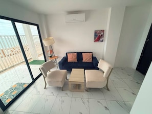 Una sala de estar moderna con un sofá azul, dos sillones, una mesa de centro y una lámpara de pie.