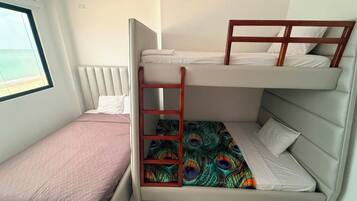 A bunk bed room with a window, a peacock-patterned bedspread, and a ladder.