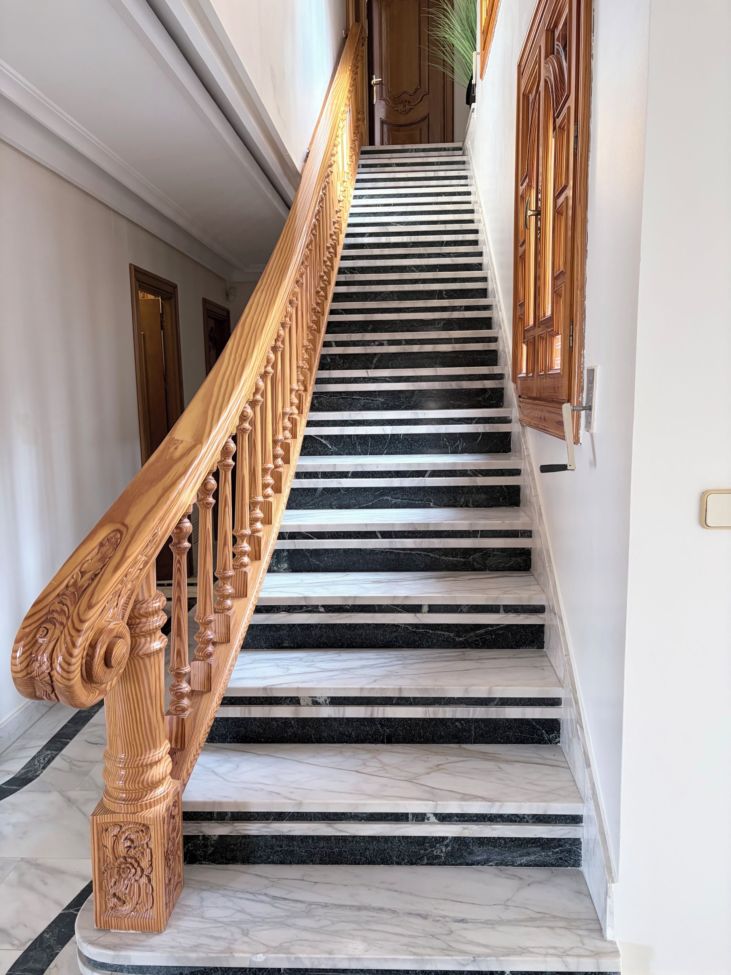 Una imponente escalera de mármol con barandilla de madera.