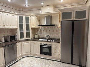 A modern kitchen with white cabinetry, a stainless steel refrigerator, a built-in oven, a microwave, and a gas stove.