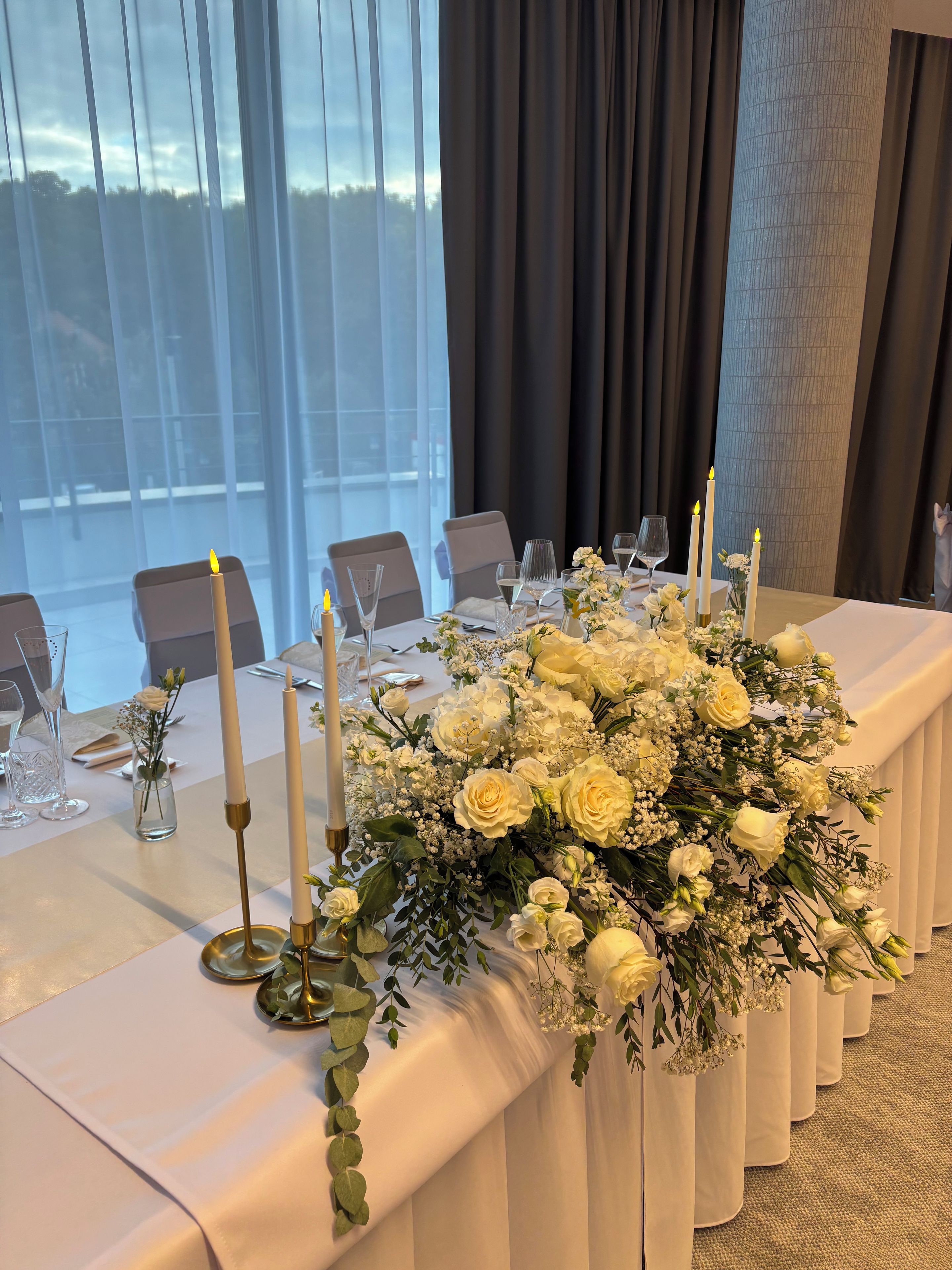A table set for a meal with candles, glasses, and a floral centerpiece.