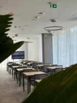 Un salón de conferencias con mesas y sillas, una pantalla grande y luces en el techo.