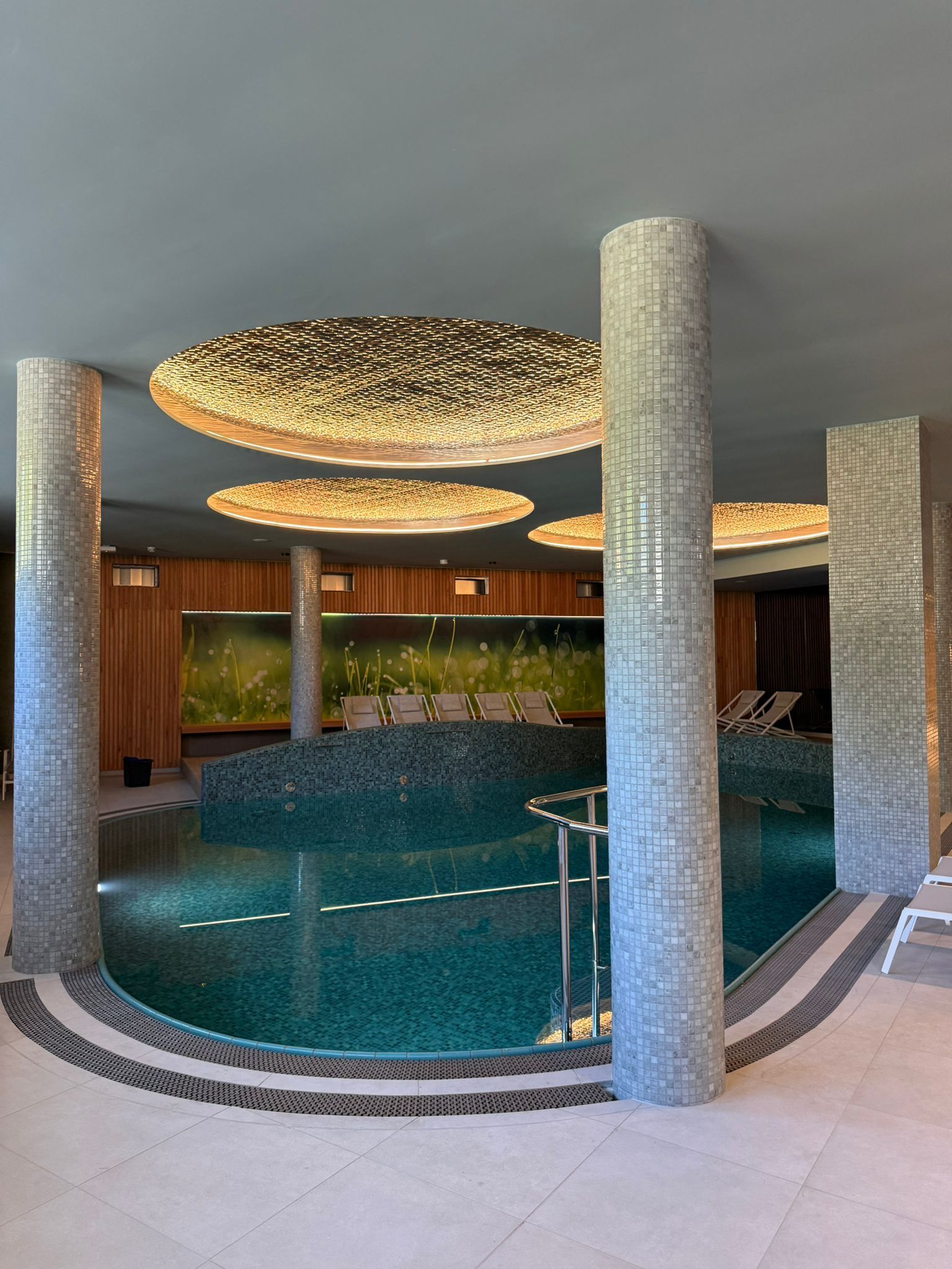 Ein moderner Innenpoolbereich mit mehreren Säulen und einem zentralen Schwimmbecken.