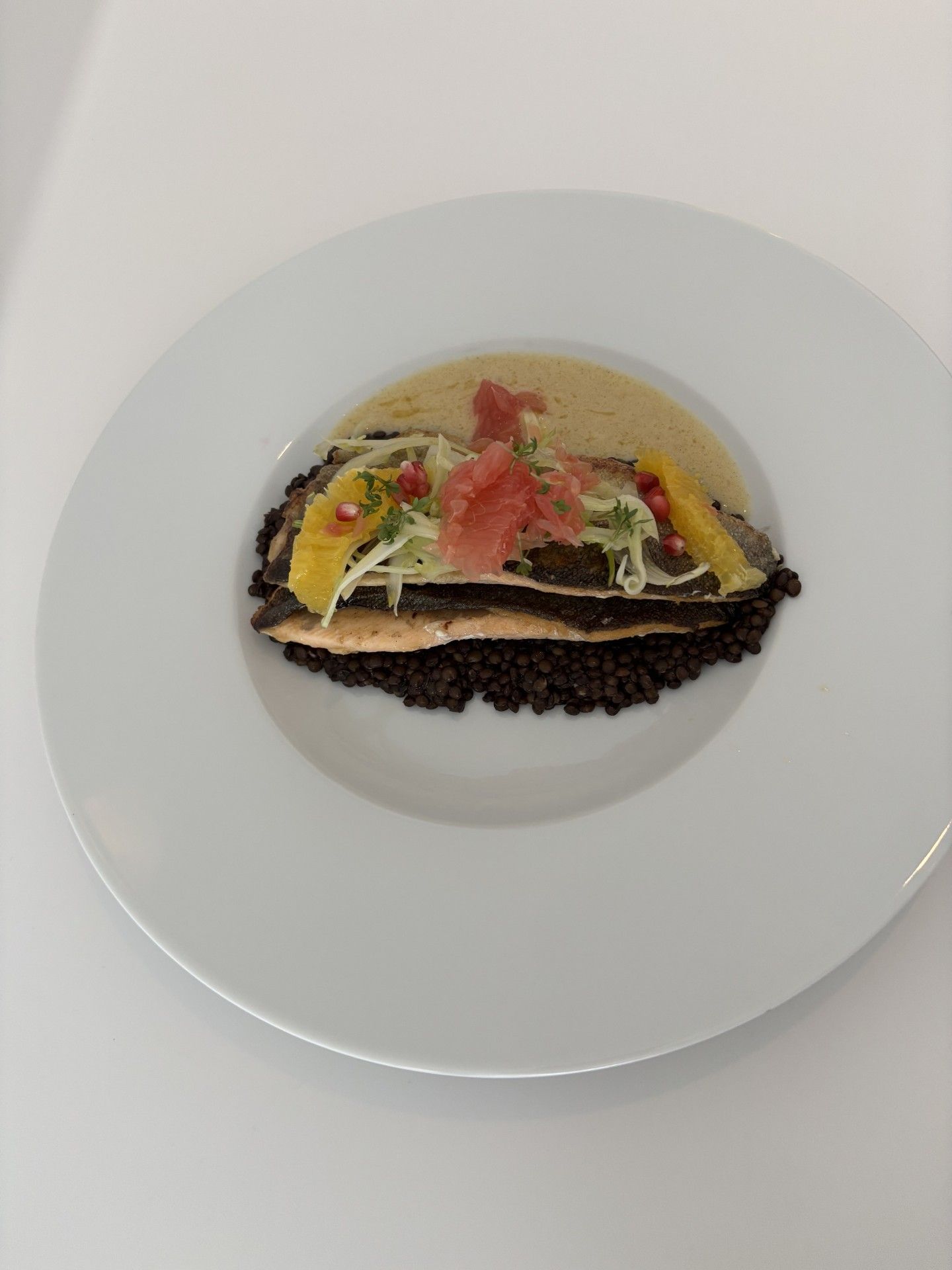 A plate with a layered dish, possibly a seafood or vegetable-based entrée, on a white plate.