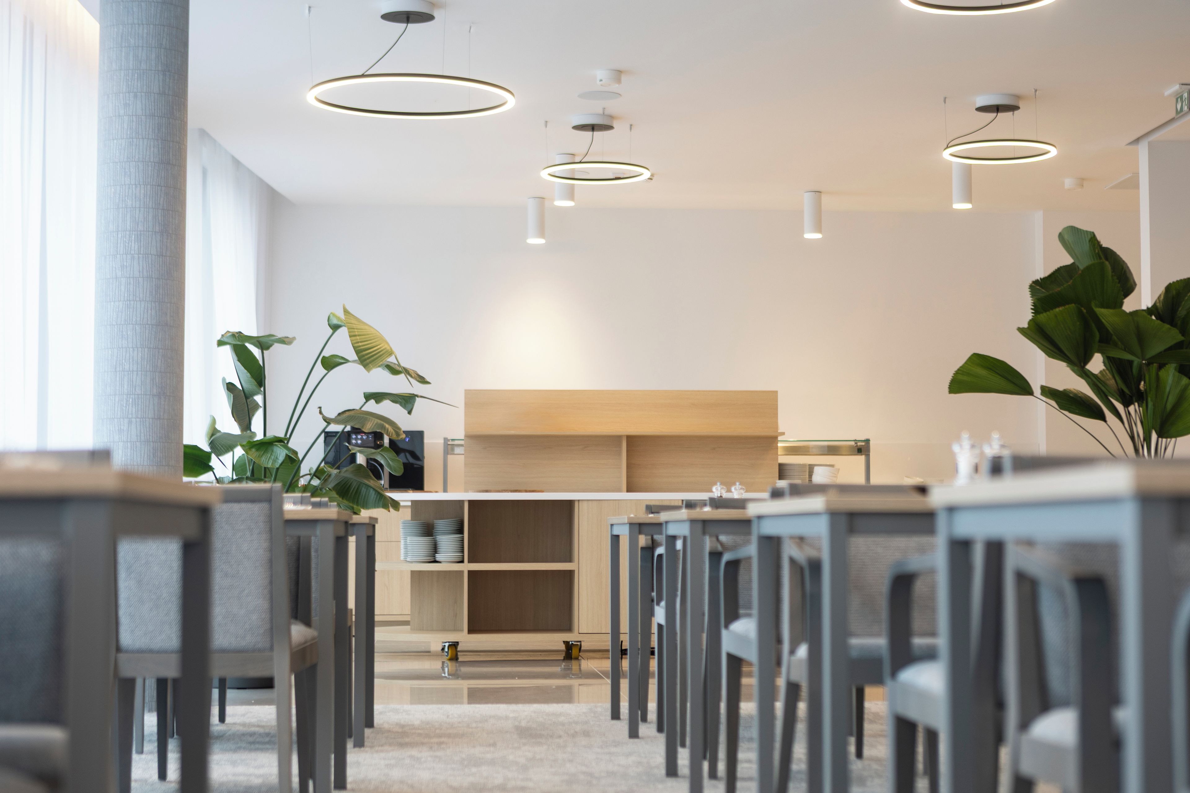 Un interior moderno con una larga mesa de comedor, sillas e iluminación colgante.