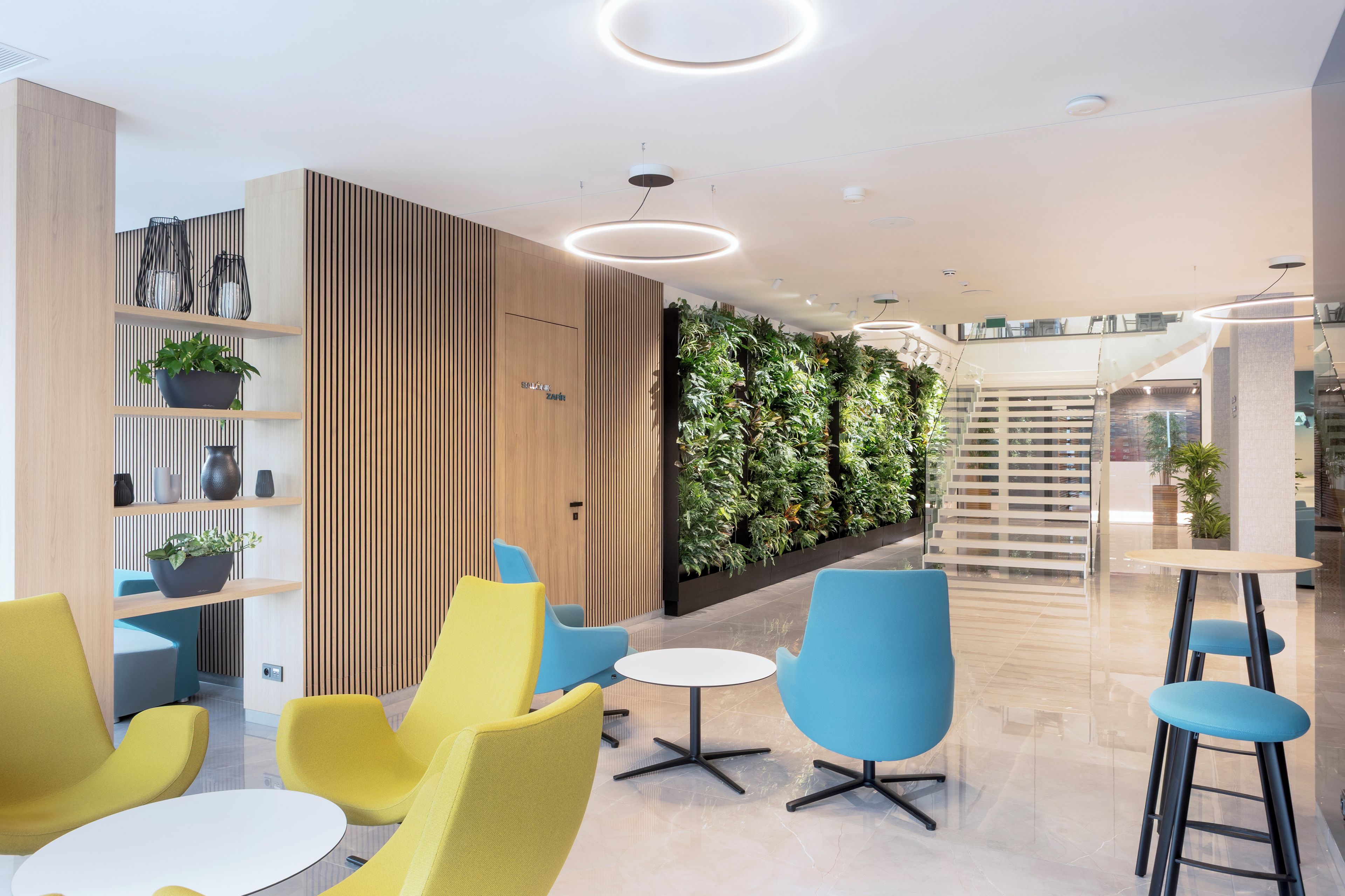 A modern lounge area with seating, a vertical garden, and a staircase.