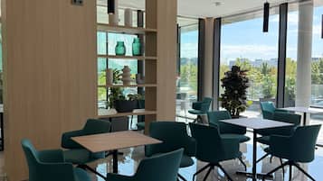 Een modern interieur met een glazen tafel en stoelen, een houten kolom en uitzicht door grote ramen.
