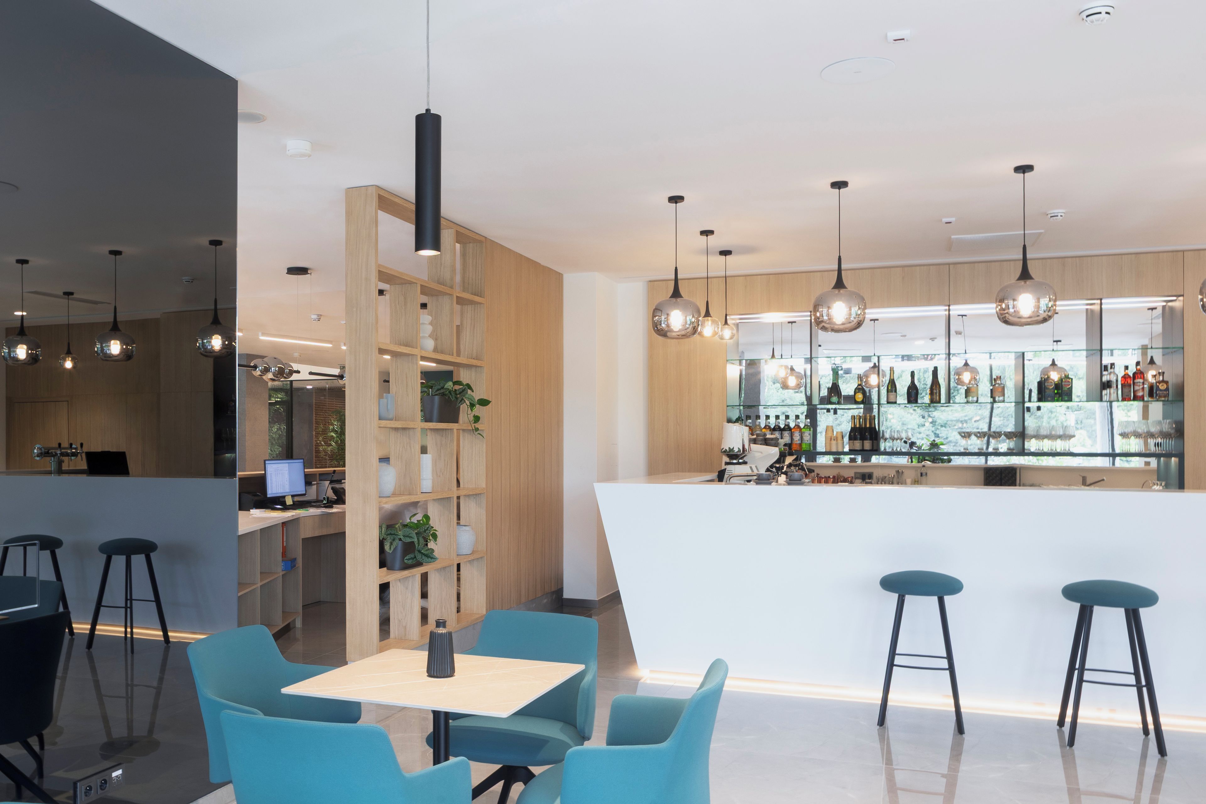 A modern bar area with a counter, stools, and hanging pendant lights.