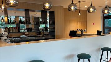 A modern bar area with a white counter, multiple hanging pendant lights, and bar stools.