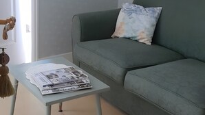 A living room with a light blue sofa, a small table with magazines, and a door with a handle.