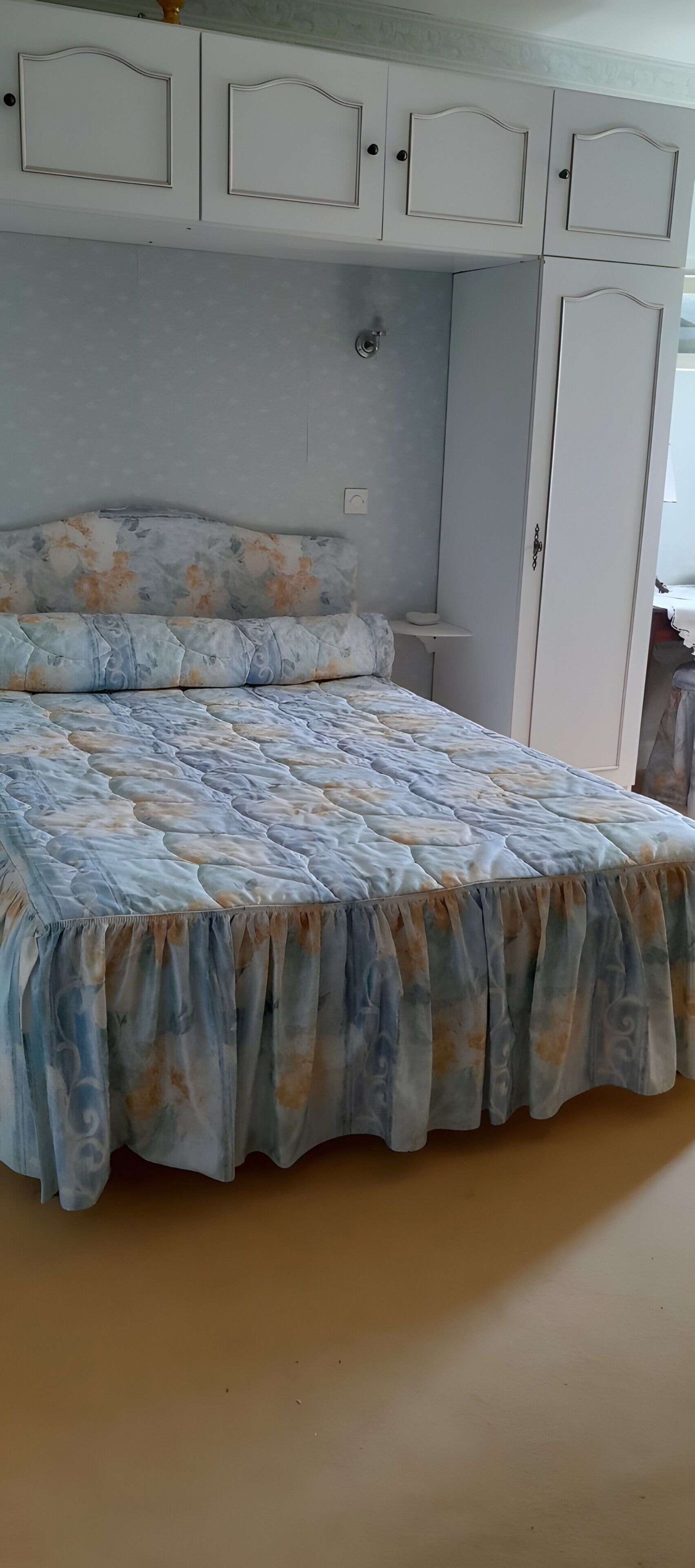 Une chambre à coucher avec un lit, une armoire et une petite table de chevet.