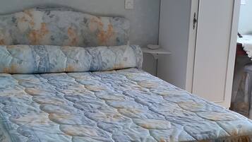 Une chambre à coucher avec un lit, une armoire et une petite table de chevet.